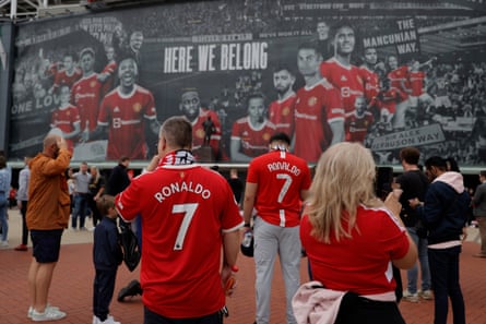 Fans gather by the huge banner on the front of Old Trafford